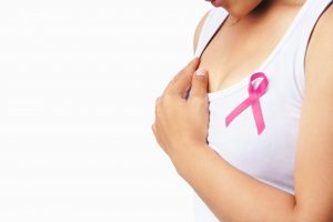 Woman holding breast with pink ribbon over white background. Concept photo to support breast cancer cause. PS: you can change the pink ribbon into red for AIDS support cause.